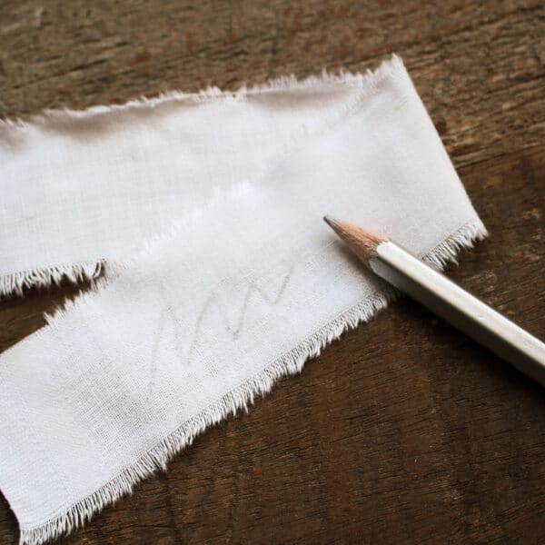 PRYM značkovací tužka stříbrná - ukázka stopy tužky na bílé látce.